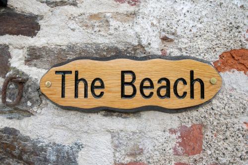 a wooden sign that reads the beach on a brick wall at Kilpatrick Glebe in Crossabeg