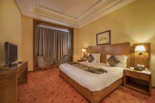 a hotel room with a large bed and a television at Grand Mogador Sea View & Spa in Tangier