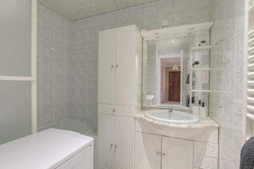 a white bathroom with a sink and a mirror at Le Parilly - Ma Cabotte in Vénissieux