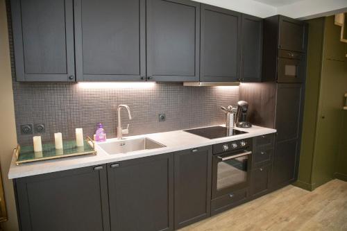 - une cuisine avec des placards noirs et un évier dans l'établissement Duplex Luxueux Saint-Germain, à Paris