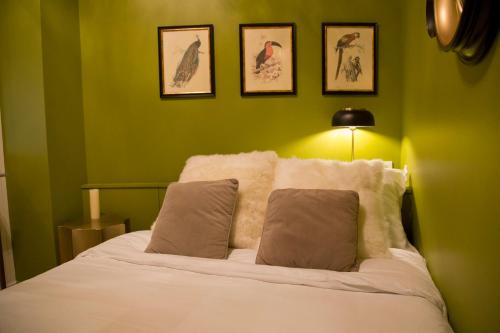 - une chambre avec des murs verts et un lit avec deux oreillers dans l'établissement Duplex Luxueux Saint-Germain, à Paris