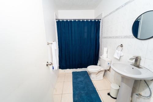 a bathroom with a toilet and a blue shower curtain at Belle air Seaview 1 BDRM -2 Queen in Runaway Bay