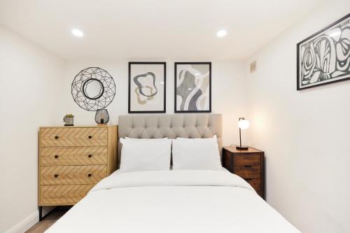 a white bedroom with a large bed and a dresser at The Bermondsey Place - Cozy 2BDR Flat in London