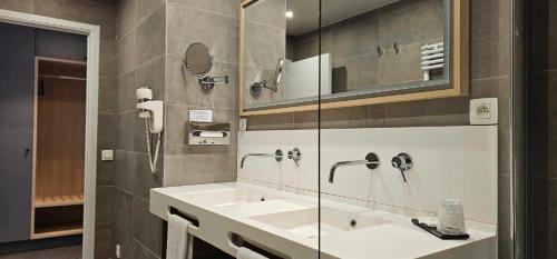 a bathroom with two sinks and a mirror and a shower at Hotel Les 3 Cles in Gembloux