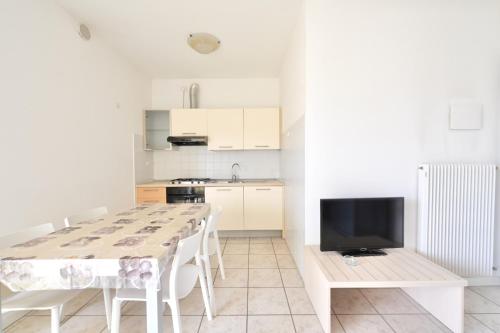 une cuisine avec une table et des chaises ainsi qu'une télévision dans l'établissement Tiepolo Apartments, à Lido di Jesolo