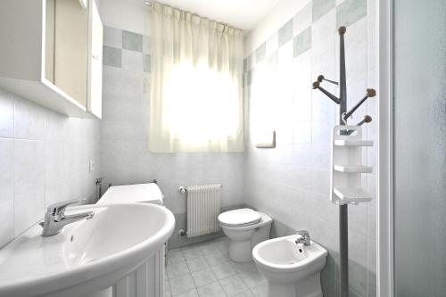 La salle de bains blanche est pourvue d'un lavabo et de toilettes. dans l'établissement Tiepolo Apartments, à Lido di Jesolo