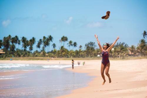 a woman jumping in the air on the beach at Vila Galé Resort Marés - All Inclusive in Guarajuba