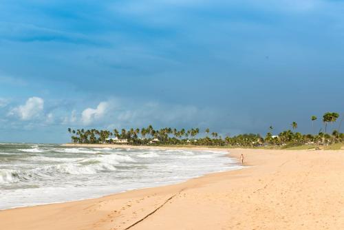a sandy beach with palm trees and the ocean at Vila Galé Resort Marés - All Inclusive in Guarajuba