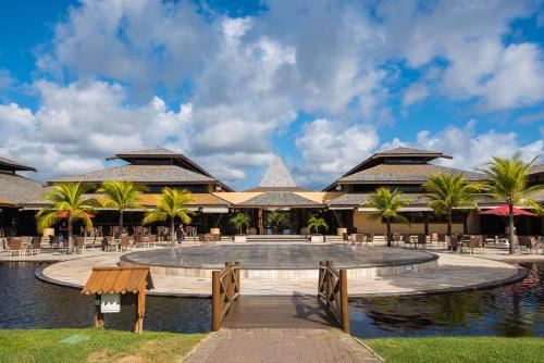 a resort with a pool and tables and palm trees at Vila Galé Resort Marés - All Inclusive in Guarajuba