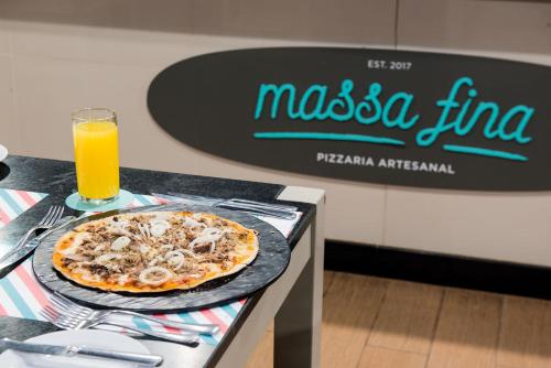 a pizza on a counter with a glass of orange juice at Vila Galé Resort Marés - All Inclusive in Guarajuba