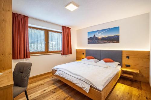 Sand in TaufersにあるApp Hubertus - Sonnklarのベッドルーム1室(ベッド1台、椅子付)