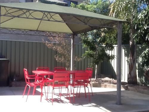 a red table and chairs under a green umbrella at The Retreat on Matthew in Batehaven