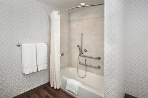 La salle de bains est pourvue d'une baignoire, d'une douche et de serviettes. dans l'établissement Hilton Garden Inn Burbank Downtown, à Burbank