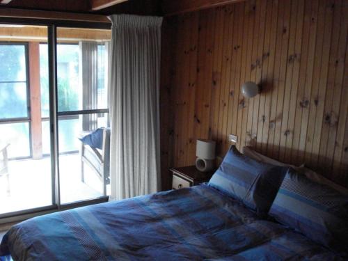 a bedroom with a bed and a sliding glass door at The Retreat on Matthew in Batehaven