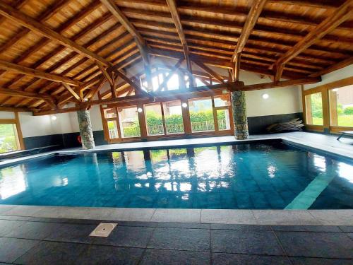 - une grande piscine dans un grand bâtiment avec fenêtres dans l'établissement Appartement cosy avec piscine, terrasse et parking, proche du centre et des commodités, arrêt ski-bus à 50m - FR-1-624-149, à Samoëns