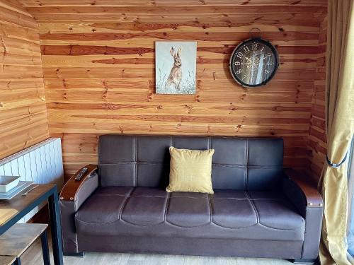 a leather couch sitting in a room with a clock at Lakeside Fishing Retreats in Boston