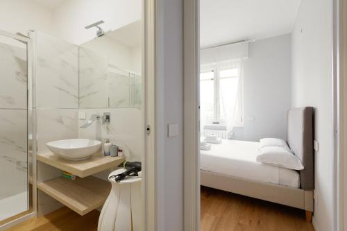 a white bathroom with a sink and a bed at GuestHost - Cimiano M2 Balcony Apartment in Milan