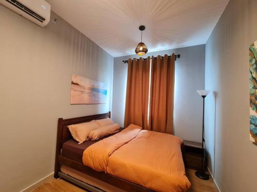 a bedroom with a bed with an orange blanket at Luxury Tangerine Suites KLIA in Sepang