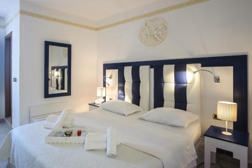 a bedroom with a white bed with a black and white headboard at Hotel Caserta Antica in Caserta