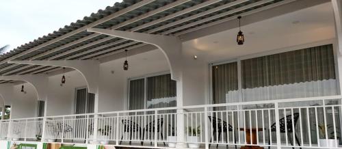 une maison blanche avec une terrasse couverte et des fenêtres dans l'établissement Cloud bed holidays, à Munnar