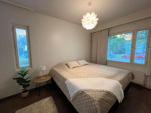 a bedroom with a bed and a chandelier at Viihtyisä kaksio Annalassa, Free parking & Sauna in Tampere