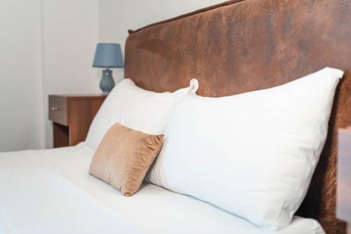 a bed with white pillows and a wooden headboard at Kairos Hotel in Pianura