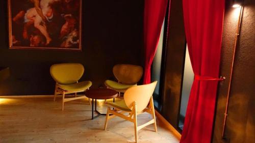 Rozafa Fish City Hotel في Labinot i Poshtëm: مجموعة من الكراسي في غرفة مع ستائر حمراء