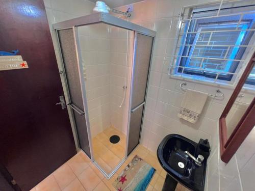 a shower with a glass door in a bathroom at Bida's House Caiobá in Matinhos