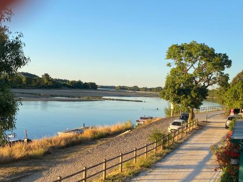 a river with cars parked next to a fence at Maison du pêcheur , située sur les bords de la Loire dans un lieu calme et paisible. in Rochefort-sur-Loire