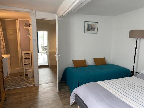 a bedroom with a bed with a blue blanket at Maison du pêcheur , située sur les bords de la Loire dans un lieu calme et paisible. in Rochefort-sur-Loire