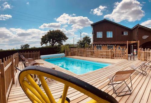 une terrasse en bois avec une piscine et une maison dans l'établissement Camping Syl-Vallée Western Village, à Bouglon
