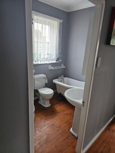 a bathroom with a tub and a toilet and a sink at 9 Lourens River in Cape Town