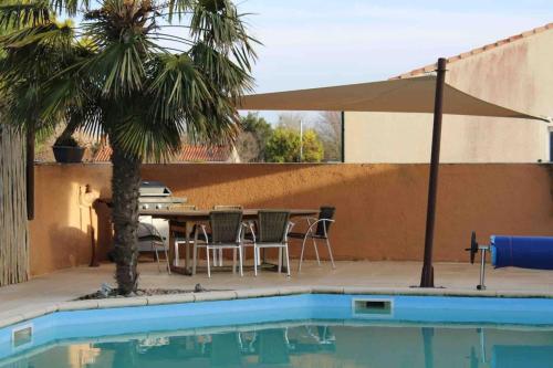 - une terrasse avec une table et un parasol à côté de la piscine dans l'établissement Villa classée 4* Piscine/Spa/Sauna/Salle de sport, à Longeville-sur-Mer