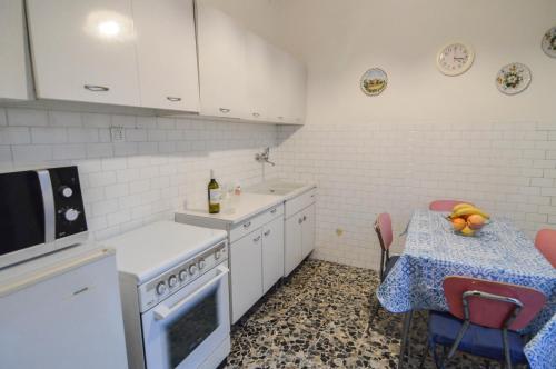 eine Küche mit einem Tisch, einer Spüle und einem Herd in der Unterkunft CASA VACANZE NONNO ASTERIO in Monfalcone