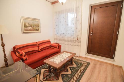 a living room with a red couch and a table at CASA VACANZE NONNO ASTERIO in Monfalcone