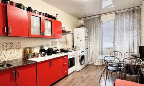 uma cozinha com armários vermelhos, uma mesa e cadeiras em VIP apart 572 em Tbilisi