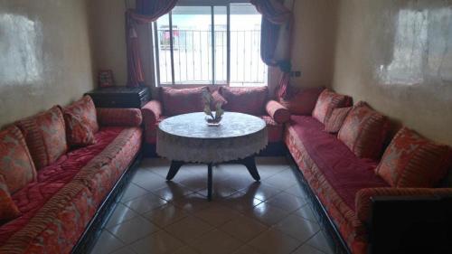 una sala de estar con sofás rojos y una mesa. en salam, en Agadir