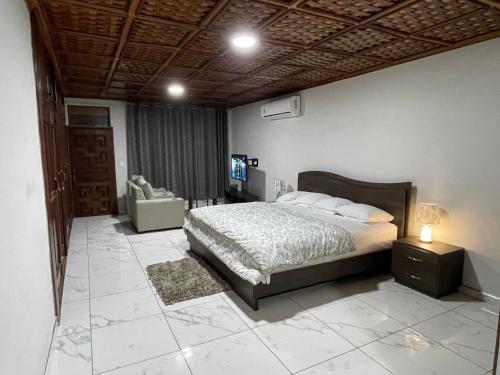 ein Schlafzimmer mit einem Bett und einem Stuhl in einem Zimmer in der Unterkunft Amazing Grace Villa in Accra