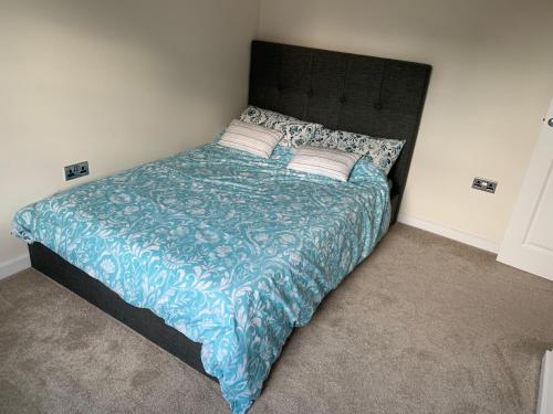 a bedroom with a bed with a blue comforter and pillows at 3 Lace Avenue LE11 2FE in Loughborough