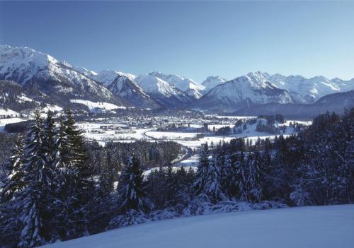een uitzicht op een met sneeuw bedekte bergketen met een stad bij Ferienhotel Sonnenheim in Oberstdorf
