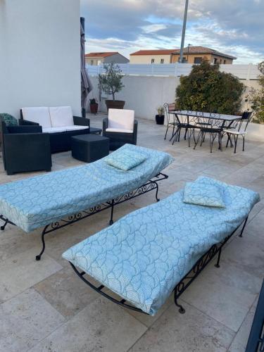 - 3 lits sur une terrasse avec des tables et des chaises dans l'établissement Dépendance de charme, à Pia