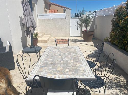 een patio met een tafel en stoelen en een parasol bij Dépendance de charme in Pia