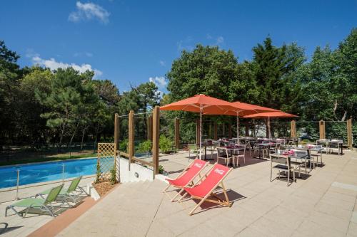a patio with chairs and umbrellas next to a pool at Résidence Valdys Thalasso & Spa - les Pins in Saint-Jean-de-Monts