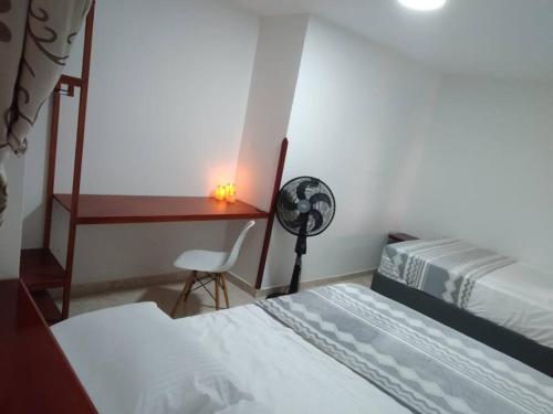 een slaapkamer met 2 bedden, een bureau en een ventilator bij Casa bonita en San Gil in San Gil