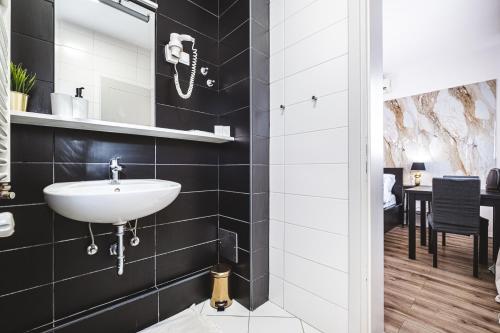 a bathroom with a white sink and black tiles at National Plus in Zagreb