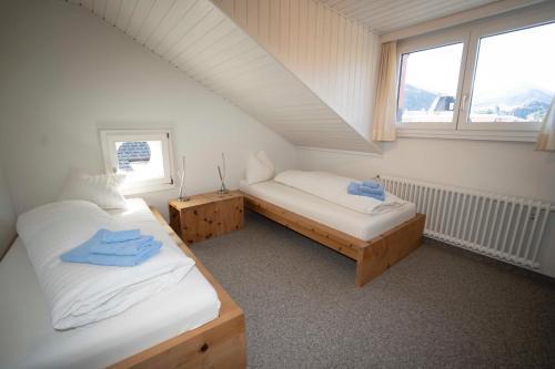 um quarto no sótão com 2 camas e uma janela em Villa Hartenfels 3 em Scuol