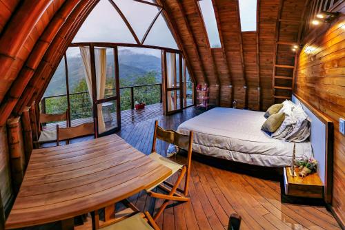 a bedroom in a log cabin with a bed and a table at Glamping Corazón del Molino in Ubaque