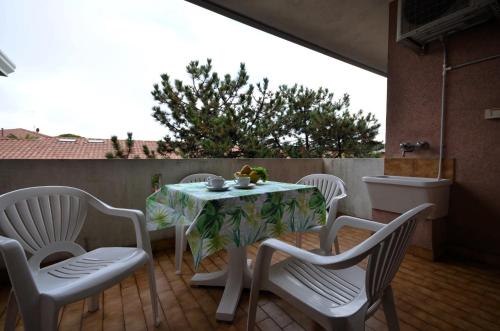 een tafel en vier stoelen op een patio met een tafel en stoelen bij Residenza Orsa Maggiore in Lignano Sabbiadoro