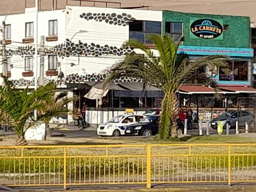 a street with cars parked in front of a building at Hotel La Carreta Playa Brava in Iquique