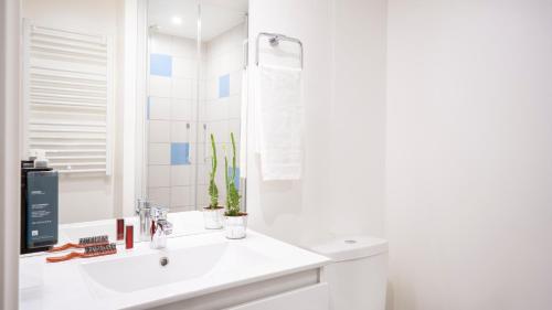 La salle de bains blanche est pourvue d'un lavabo et d'un miroir. dans l'établissement Séjours & Affaires Paris Bagnolet, à Bagnolet